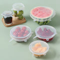Six clear silicone stretch lids covering bowls, jars and a cut watermelon