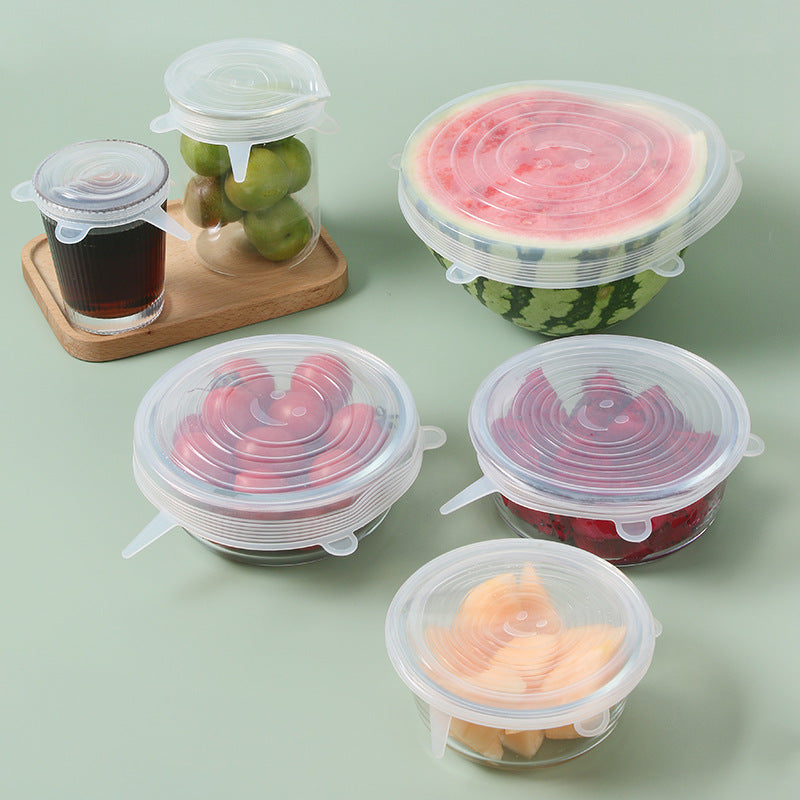 Six clear silicone stretch lids covering bowls, jars and a cut watermelon