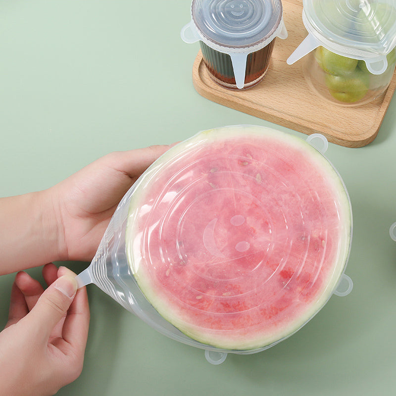 Hands stretching a silicone lid over a cut watermelon
