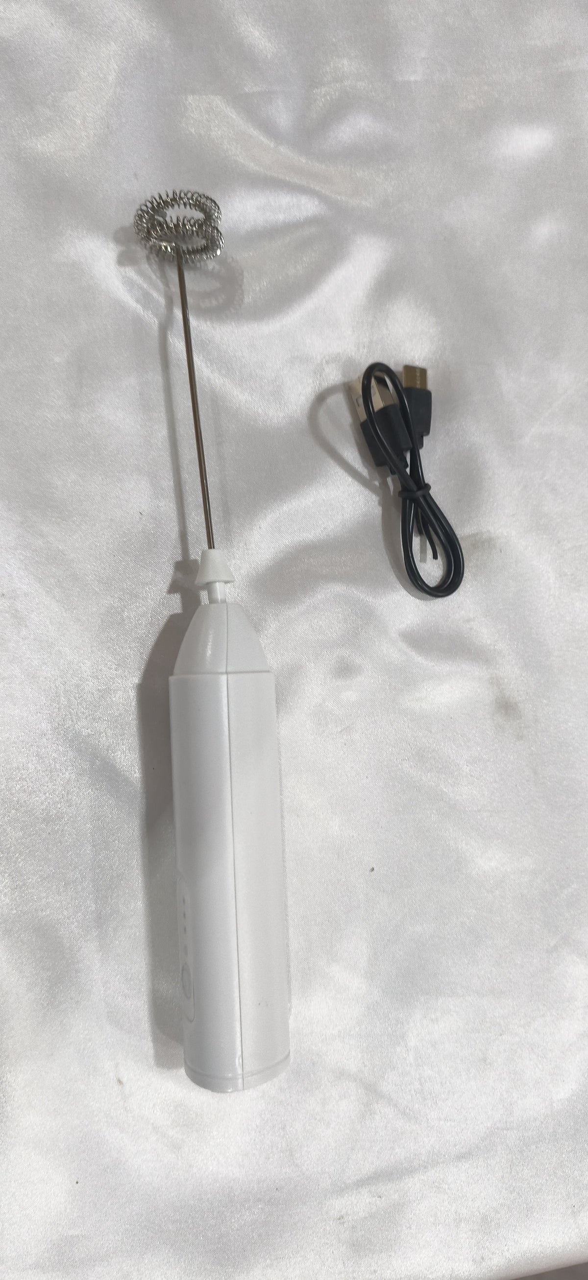 White milk frother with its charging cable, from another angle